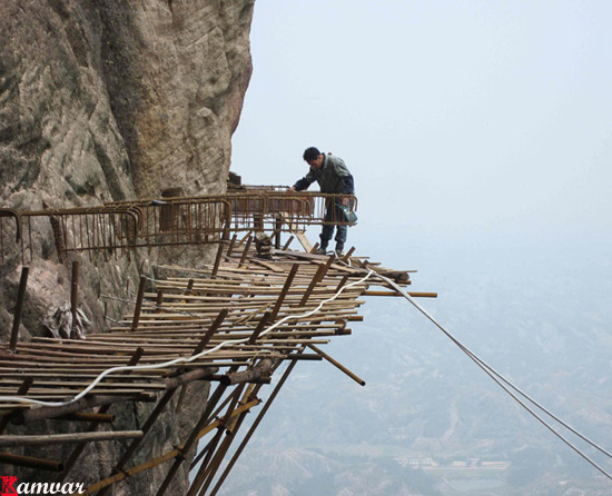 Workers build a plank road on the side of Shifou Mountain, Huna